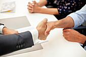 Nahaufnahme eines Immobilienmaklers beim Händeschütteln mit einem männlichen Kunden während einer Besprechung