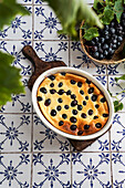 Red grape clafoutis, French cuisine. on a table of ceramic tiles with a blue pattern