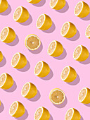 Full frame background with juicy lemon halves set against a bright pink background