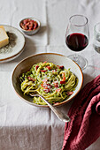 Schüssel Spaghetti mit Basilikum, Pancetta und Parmesan, serviert mit einem Glas Rotwein und Wasser