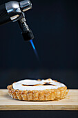 A blow torch browning the top of a meringue tart