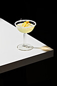 Lemon cocktail on a white table and black background