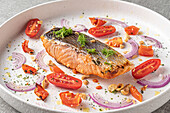 Cooked salmon slice with tomatoes and onions