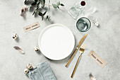 Banner. Table setting. A fashionable minimalistic plate with a linen napkin, Knife and fork, Easter eggs and feathers on a gray background. Top view. Happy Easter holiday concept for cafes and restaurants. Copy space