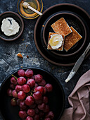 Grapes and cream cheese toast with honey on black plates