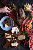 Healthy probiotic cheese platter with kimchi, dark coloured sourdough bread and fermented vegetables. Male hand reaching for the food
