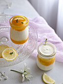 Lemon curd and greek yogurt with thyme in glass jars. Soft romantic scene.