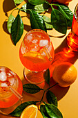 Aperol Spritz cocktail with ice, a misted refreshing drink, on an orange background, sunlight, shadows, a summer drink in a wine glass