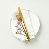 Gold Cutlery with eucalyptus branches on white plate with napkin over light grey Background. Minimalistic design. Copy Space