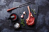 Raw fresh meat Veal rib and seasonings on black stone slate on dark background