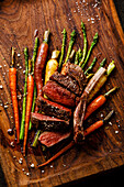 Grilled sliced Venison Ribs with baked vegetables on wooden background