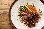 Grilled Venison Ribs with baked vegetables on wooden background