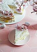 Crepe cake or blini cake for Easter, pink background, almond blossoms, pink background, women's hands