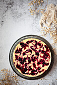 A baked cheesecake with fruit ripple on a grey serving plate.