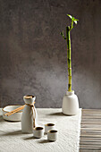 Japanese sake still life with a bamboo branch, light-coloured linen background, Asian ceremony