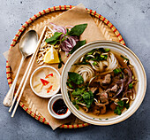 Pho Bo, vietnamesische Suppe mit Rindfleisch in einer Schale auf einem Betonhintergrund