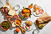 Charcuterie-Brett mit Oliven, Wurstwaren, Käse, Brot und Orangen auf einem Marmorhintergrund