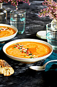 Red lentil and piquillo pepper bisque in white bowls with blue napkins