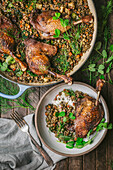 Duck Legs on top of lentils in casserole and serving dish with pea shoots garnish