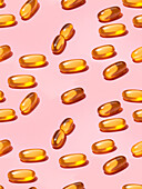 Composition of orange vitamin pills on a pink background in a bright studio viewed from above