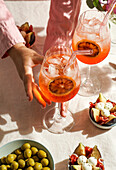 Aperol Spritz cocktail, on a pale pink linen tablecloth, shade, sunlight, summer drink in a glass