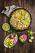 Mexican casserole in a cast-iron pan with toppings and avocado