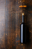 Wine bottle and corkscrew on dark wooden background