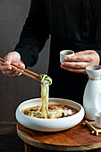 Japanese sake composition with Asian soup with rice noodles, Asian meal ceremony with magnolia flowers