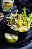 Healthy celery salad with apples and seeds served in the bowl in dark background