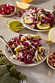 Radicchio-Salat mit Birnen, Pekannüssen, Granatapfel, Pekannüssen und Basilikum-Vinaigrette auf neutralem braunen Hintergrund mit grünem Tuch