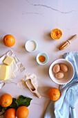 Backvorbereitung mit Zutaten für Orangen-Madeira-Kuchen auf weißem Marmortisch, mit negativem Kopierraum