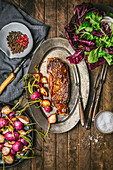 Steak au poivre with salad and roasted radishes on a metal plate