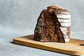 Front view of a stack of rye bread slices on a wooden chopping board against a blurred light-coloured background