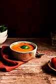 Tomato and basil soup in a bowl on a wooden table
