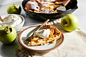 Deutscher Apfelpfannkuchen mit Pfanne und Tellern
