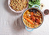 Cocido Madrileño, a traditional Spanish meal, chickpea-based stew from Madrid rose pink ceramic tile background