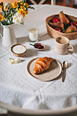 Breakfast scene with croissant, coffee, yogurt and fruit