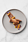 Mousse au Chocolat, Passionsfruchtquark, kandierte Haselnüsse, Kakaonibs-Praline, Passionsfruchtgel, getrocknete Schokolade
