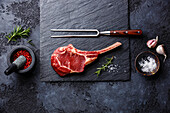 Raw fresh veal rib steak with bone and spices on a dark background