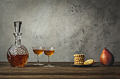 Sherry in old glasses and decanter with a stack of biscuits and a pear