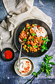 Braised Eggplant (aubergine) and chickpea Stew in serving bowl with yogurt swirl and mint garnish