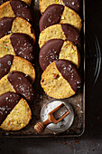 A vintage baking tray holding chocolate dipped pistachio cookies that have been sprinkled with sea salt.