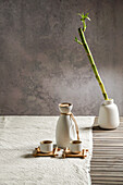 Japanese sake still life with a bamboo branch, light-coloured linen background, Asian ceremony