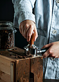 Barista holding portafilter and coffee tamper making coffee in coffee shop or cafe, dark backgrounds