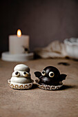 Geister- und Fledermaus-Bonbons für Halloween; mit Keksboden, Dulce de Leche-Füllung und Schokoladenüberzug.