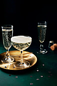 Prosecco glasses and golden plate on a green background