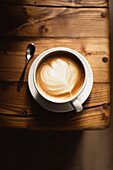 Coffee in white cup on wooden table, with spoon