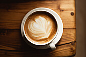 Coffee in a white cup on a wooden table, with spoon