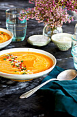 Red lentil piquillo pepper bisque in white bowls with blue napkins