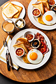 Komplettes englisches Frühstück mit Spiegeleiern, Würstchen, Speck, Bohnen und Toast